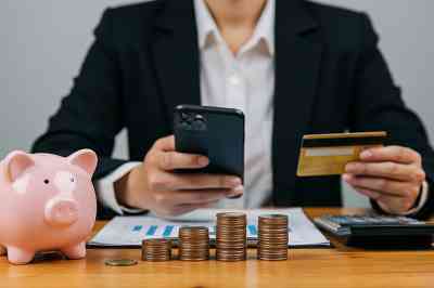 Mann mit Smartphone, Bankomatkarte, Sparschwein und Münzen - © Sultan - stock.adobe.com